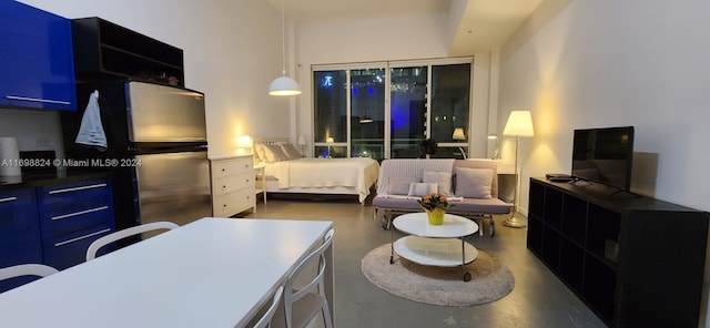 bedroom featuring stainless steel fridge and concrete flooring