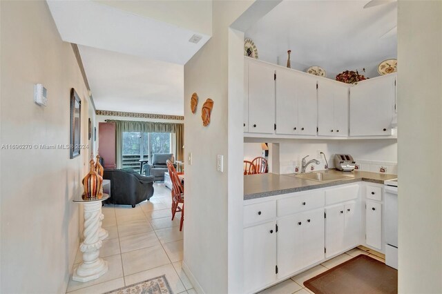 kitchen with white range oven, sink, white cabinets, and light tile patterned floors