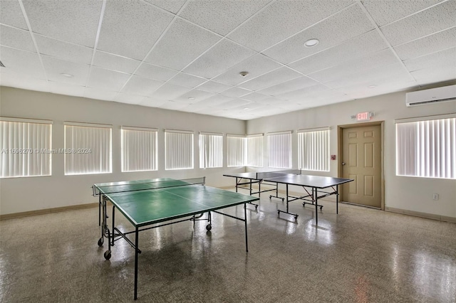 game room with a drop ceiling and an AC wall unit