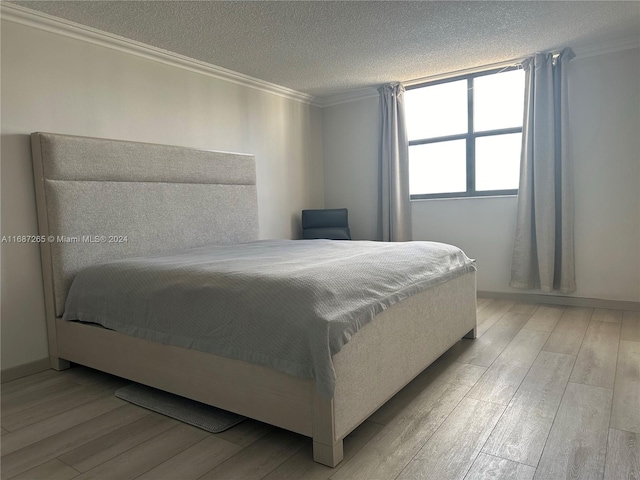 bedroom featuring crown molding, light hardwood / wood-style floors, and a textured ceiling