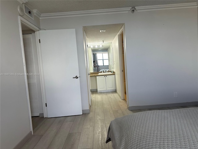 bedroom with crown molding, light hardwood / wood-style flooring, a textured ceiling, and sink