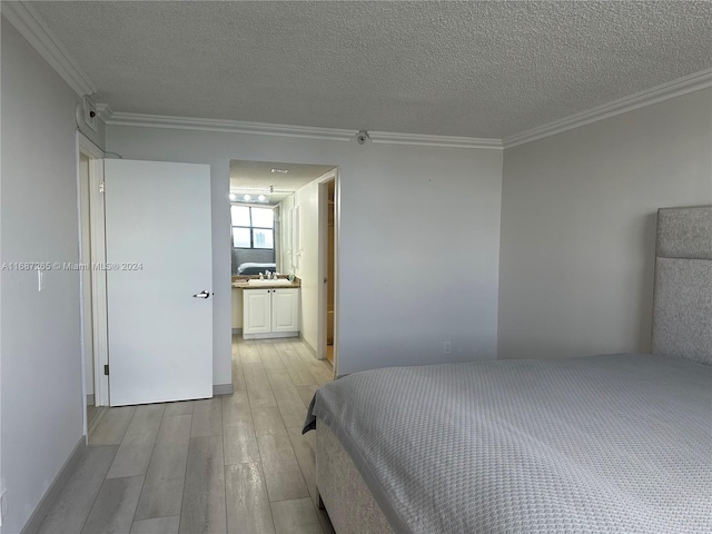 bedroom featuring a textured ceiling, light wood-type flooring, crown molding, and connected bathroom