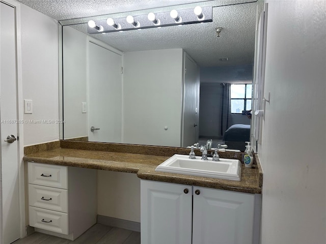 bathroom with hardwood / wood-style floors, vanity, and a textured ceiling