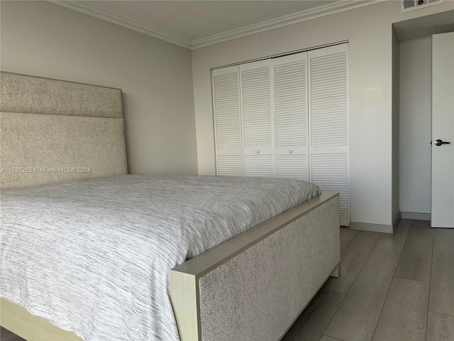 bedroom with wood-type flooring, a closet, and crown molding