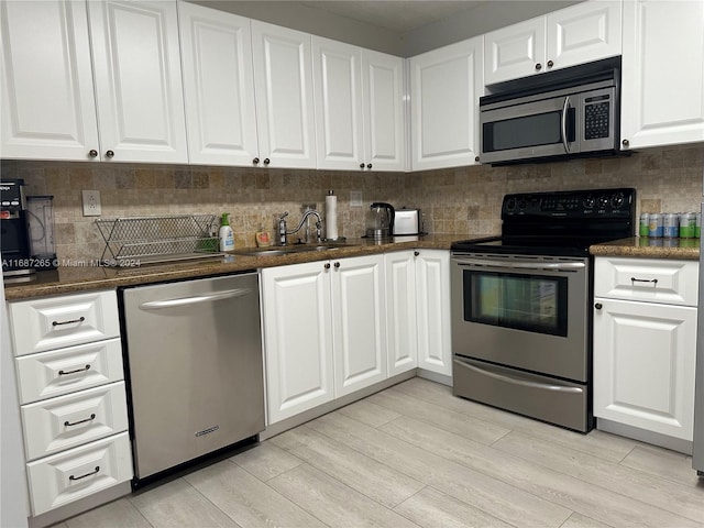 kitchen featuring white cabinets, sink, decorative backsplash, light hardwood / wood-style floors, and stainless steel appliances