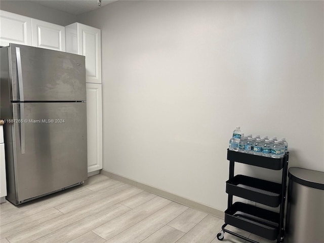 kitchen with white cabinets, light hardwood / wood-style floors, and stainless steel refrigerator