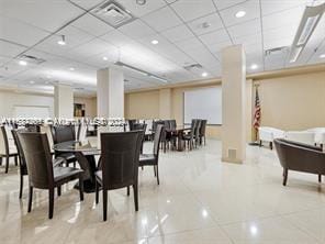 dining area featuring tile patterned floors and a paneled ceiling