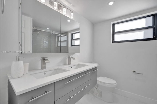 bathroom with vanity, toilet, and a shower with door