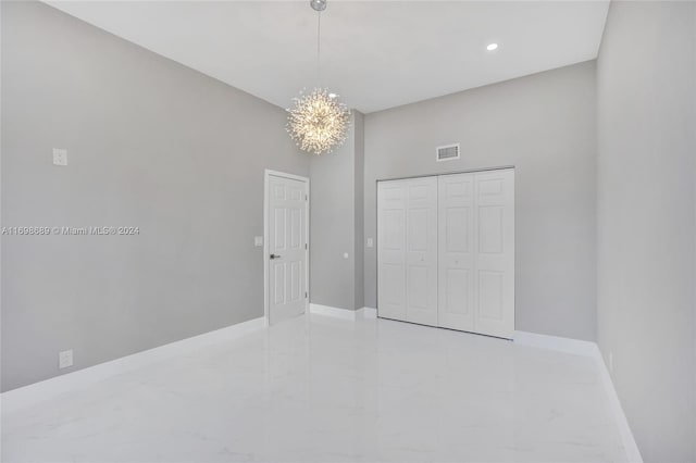 unfurnished bedroom featuring a chandelier and a closet