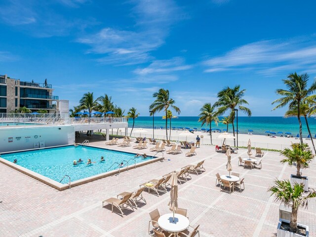 view of swimming pool featuring a beach view, a patio, and a water view