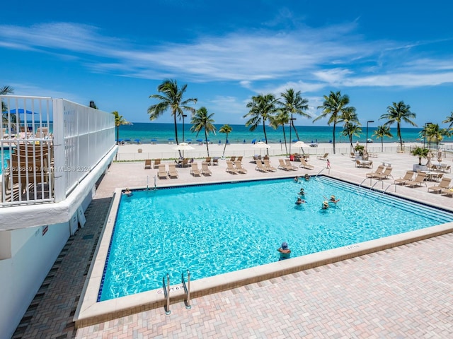 view of swimming pool with a beach view, a patio, and a water view