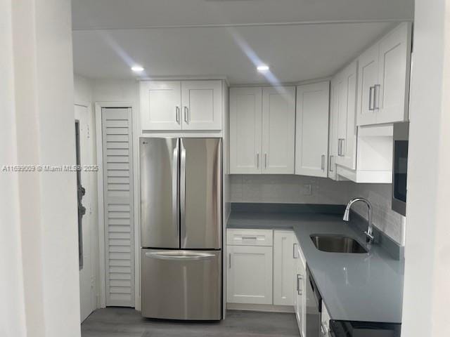 kitchen featuring stainless steel appliances, white cabinetry, hardwood / wood-style flooring, and sink