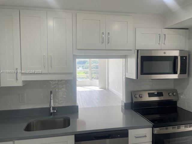 kitchen featuring tasteful backsplash, sink, stainless steel appliances, and white cabinets