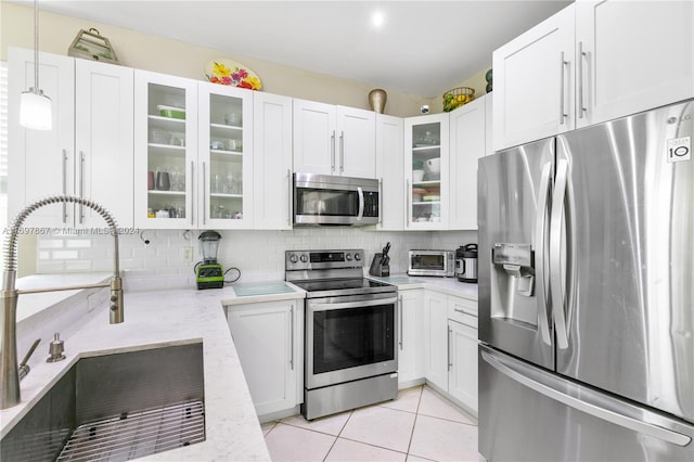 kitchen with white cabinetry, sink, light stone counters, pendant lighting, and appliances with stainless steel finishes