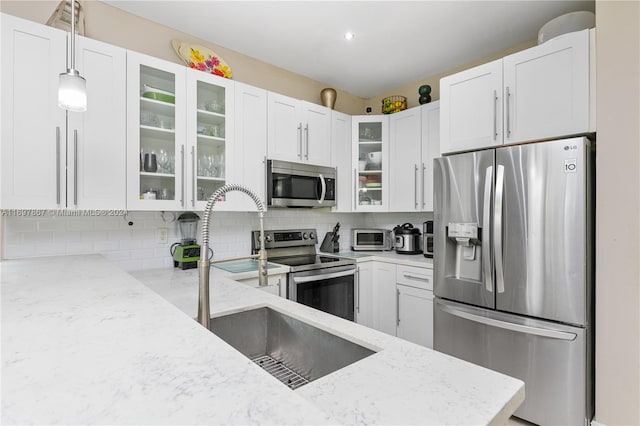 kitchen featuring tasteful backsplash, light stone countertops, pendant lighting, and stainless steel appliances