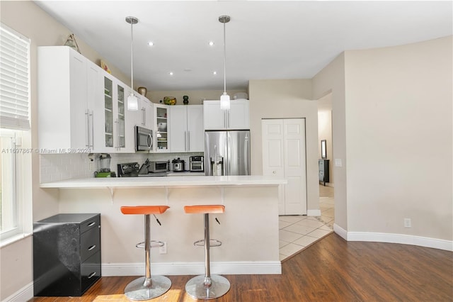 kitchen featuring a breakfast bar, white cabinets, stainless steel appliances, and dark hardwood / wood-style floors