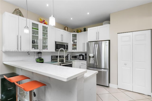 kitchen featuring kitchen peninsula, appliances with stainless steel finishes, white cabinets, and a kitchen breakfast bar