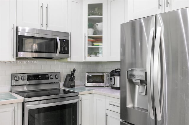 kitchen with white cabinetry, backsplash, and appliances with stainless steel finishes