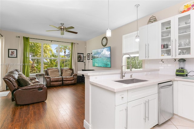 kitchen with tasteful backsplash, sink, wood-type flooring, decorative light fixtures, and white cabinetry