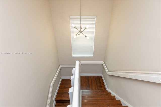 stairs featuring hardwood / wood-style floors and a notable chandelier