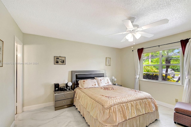 bedroom with ceiling fan and a textured ceiling