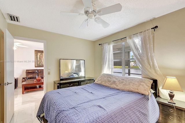 bedroom with ceiling fan and a textured ceiling