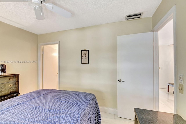 tiled bedroom featuring ceiling fan and a textured ceiling