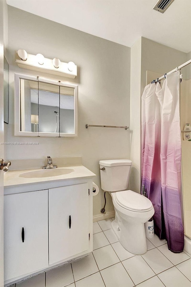 bathroom with toilet, vanity, tile patterned floors, and walk in shower