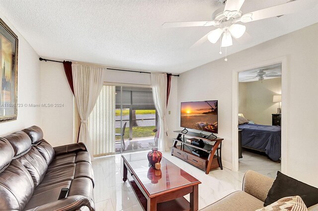 living room with ceiling fan and a textured ceiling