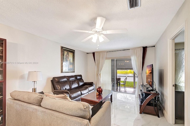 living room featuring ceiling fan and a textured ceiling