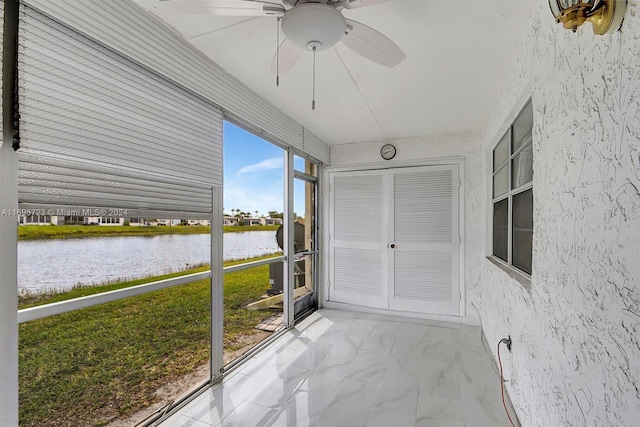 unfurnished sunroom with a water view and ceiling fan