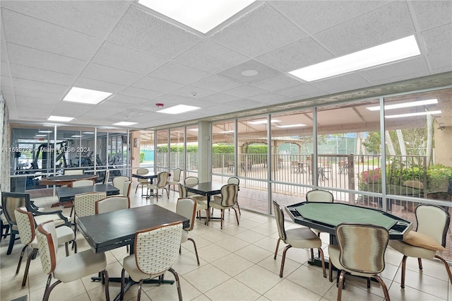 dining area with a wall of windows, a drop ceiling, and light tile patterned flooring