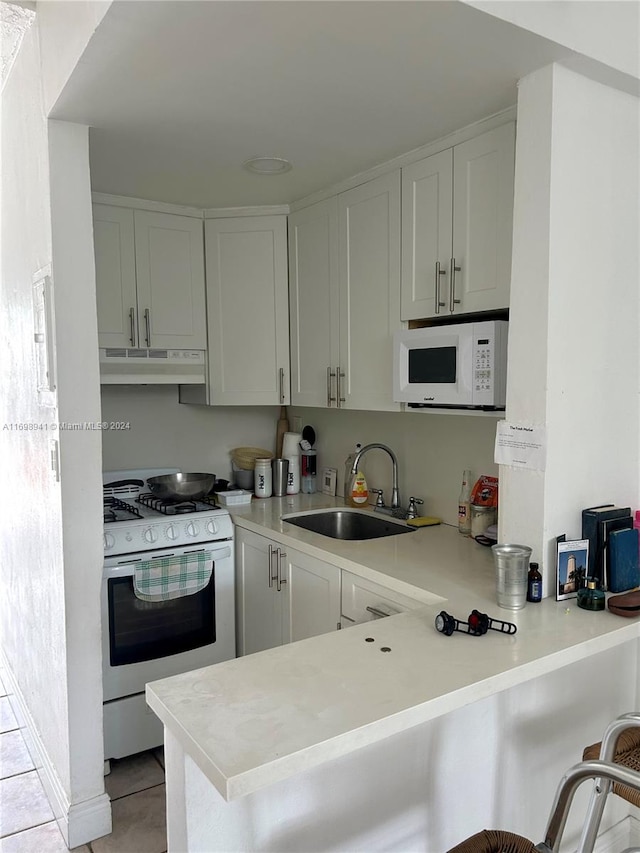 kitchen featuring a breakfast bar, white appliances, sink, kitchen peninsula, and white cabinetry