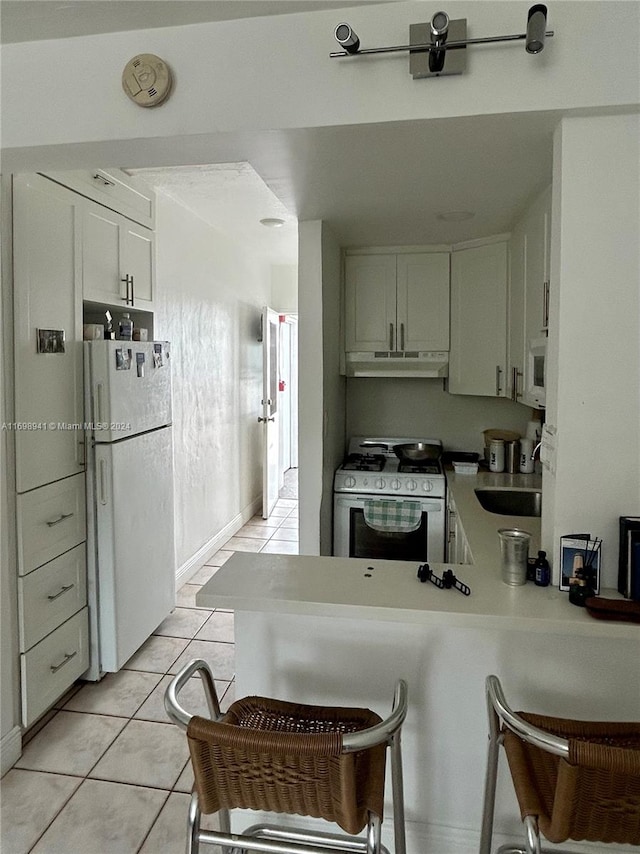 kitchen featuring white cabinetry, sink, kitchen peninsula, white appliances, and light tile patterned floors