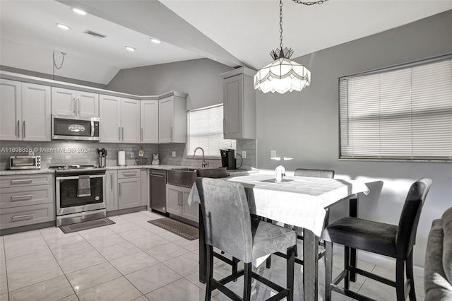 kitchen featuring gray cabinetry, appliances with stainless steel finishes, tasteful backsplash, decorative light fixtures, and light tile patterned flooring