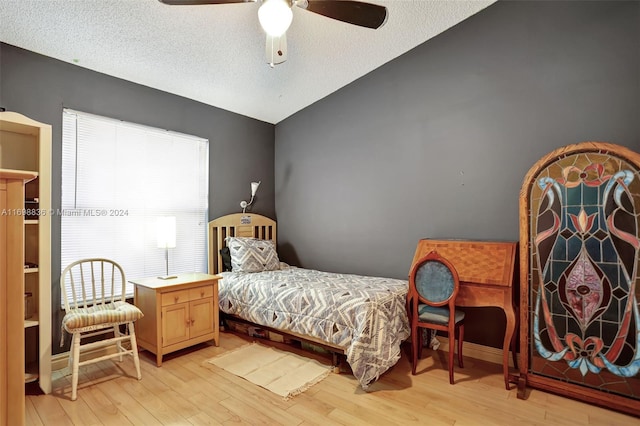 bedroom with a textured ceiling, light hardwood / wood-style flooring, ceiling fan, and lofted ceiling