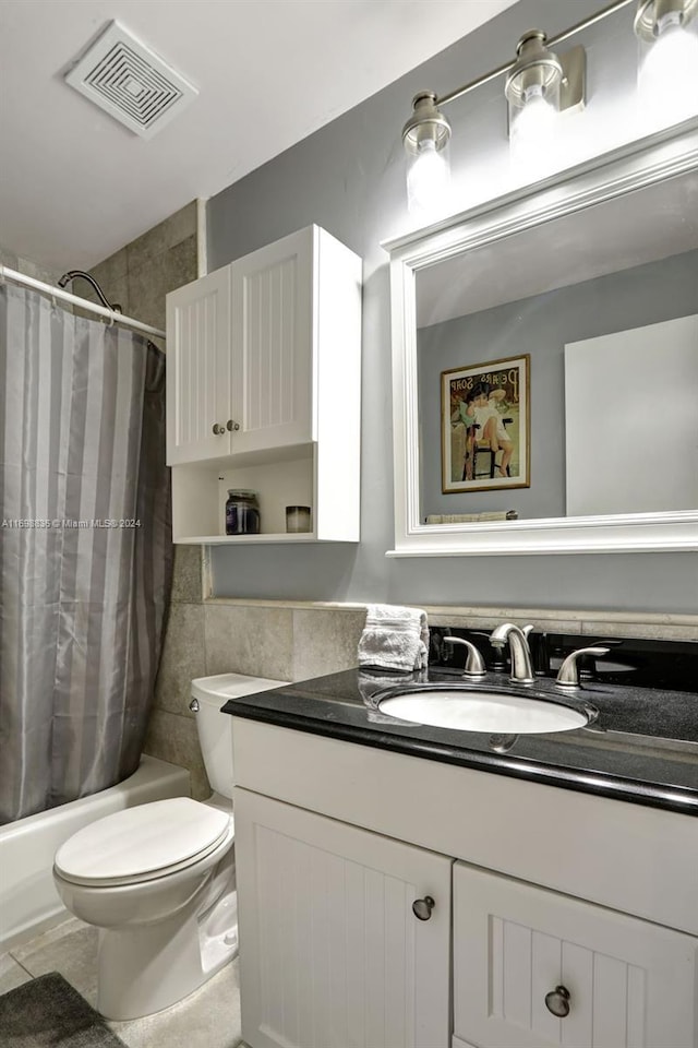 full bathroom featuring vanity, shower / bath combo with shower curtain, tile walls, tile patterned flooring, and toilet