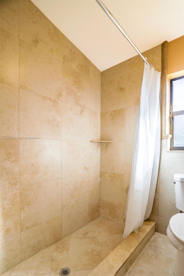 bathroom featuring tile patterned flooring, toilet, walk in shower, and tile walls