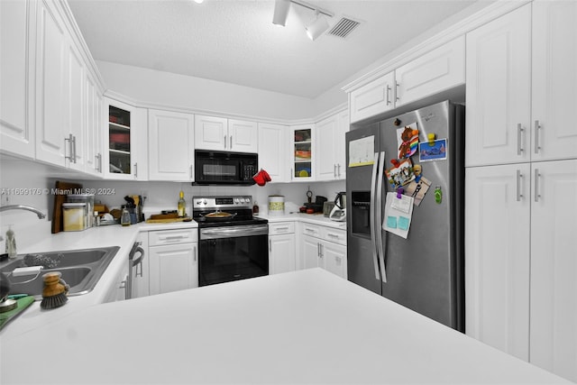 kitchen featuring sink, track lighting, a textured ceiling, white cabinets, and appliances with stainless steel finishes