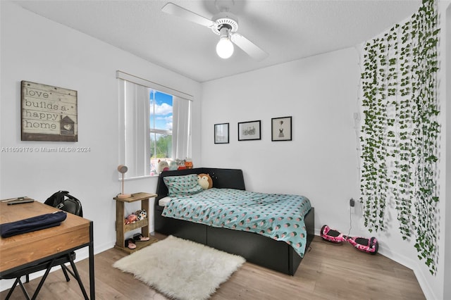 bedroom featuring ceiling fan, wood-type flooring, and a textured ceiling