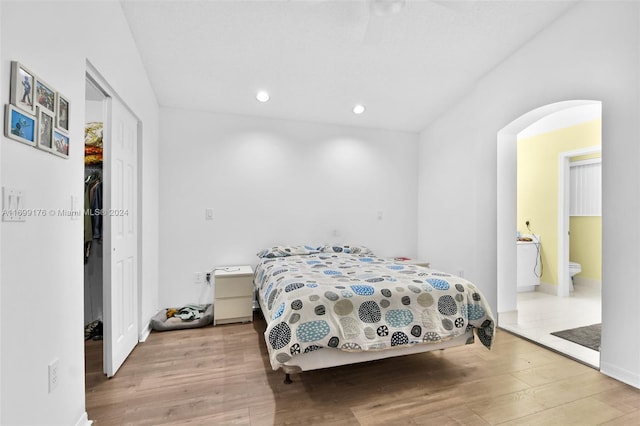 bedroom with ensuite bath, ceiling fan, a closet, and wood-type flooring