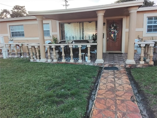 doorway to property with covered porch and a yard