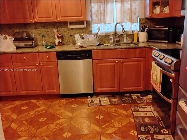 kitchen with light stone countertops, appliances with stainless steel finishes, tasteful backsplash, and sink