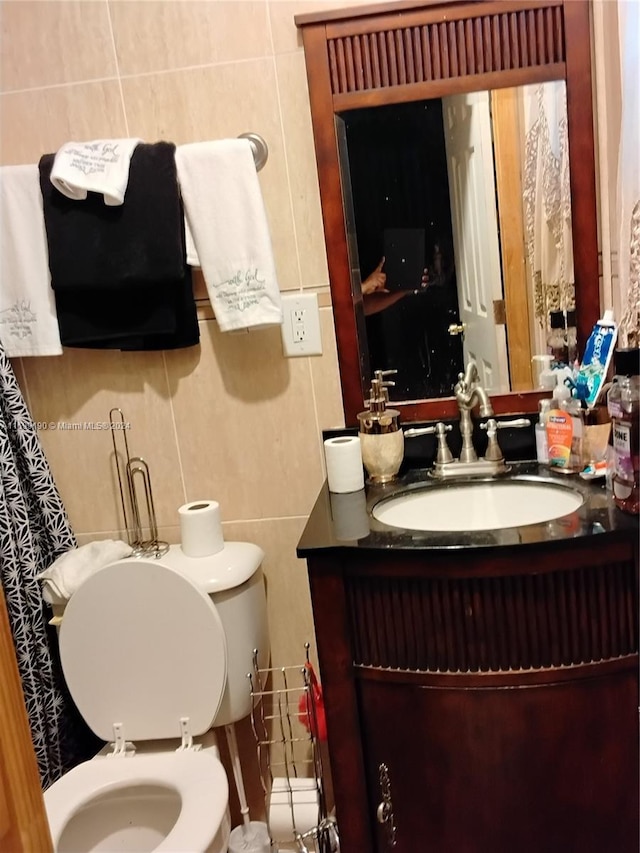 bathroom featuring vanity, toilet, and tile walls