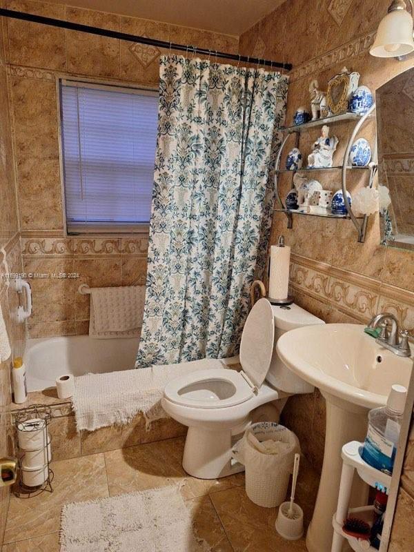 bathroom with tile patterned flooring, tile walls, and toilet