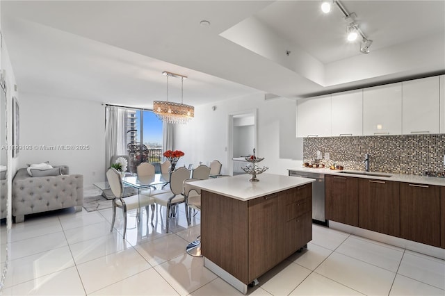 kitchen featuring hanging light fixtures, dishwasher, a kitchen island, sink, and white cabinetry