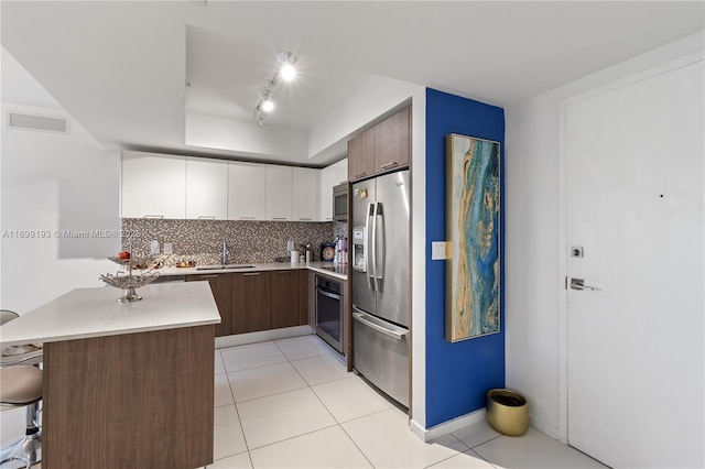 kitchen with appliances with stainless steel finishes, sink, a kitchen breakfast bar, kitchen peninsula, and white cabinets