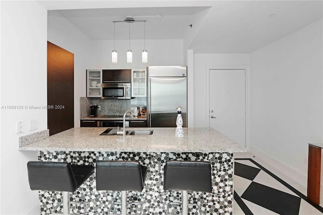 kitchen with decorative light fixtures, sink, stainless steel appliances, and a breakfast bar area