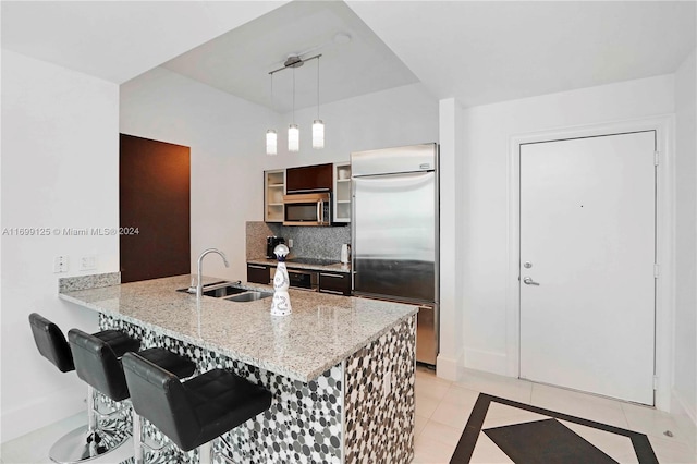 kitchen featuring kitchen peninsula, appliances with stainless steel finishes, sink, decorative light fixtures, and light tile patterned flooring