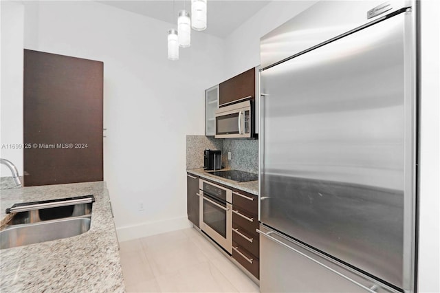 kitchen with sink, decorative light fixtures, decorative backsplash, dark brown cabinets, and appliances with stainless steel finishes